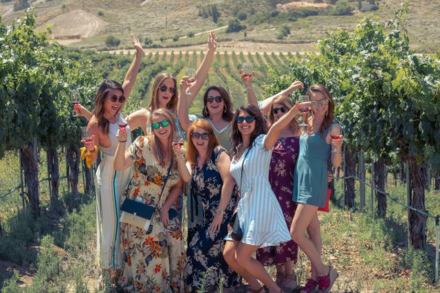 Pictured is a group of young attractive girls in a vineyard having the time of their life on a Grapeline Wine Tour. 
