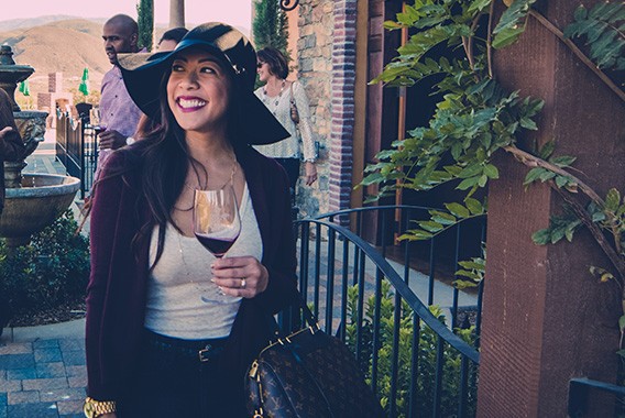 Girl in hat with red wine at winery