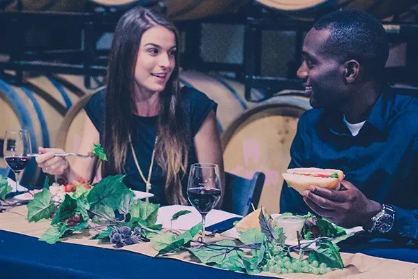 Two friends eating lunch in winery barrel room