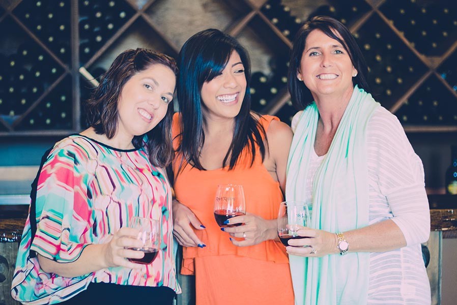 Three ladies tasting red wine at a winery