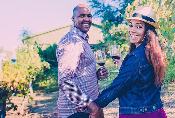 Smiling couple with wine in vineyard