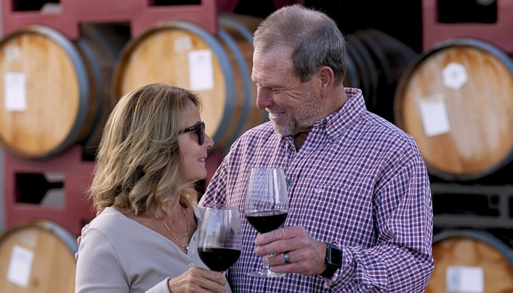 A couple experiencing a wine tasting in the barrel room.