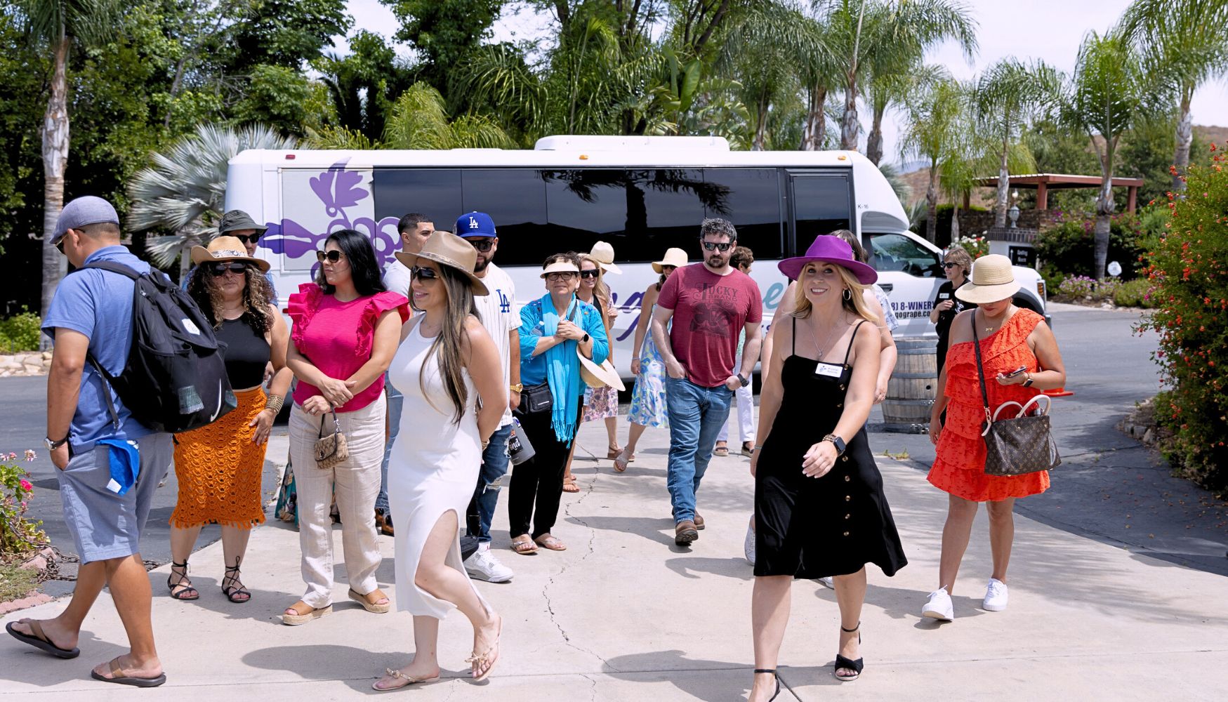 Group of people arriving from a Grapeline tour bus, preparing to explore a winery on a sunny day.