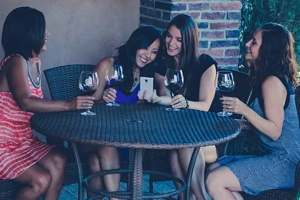 Four girlfriends take selfies and enjoy wine tastings in Viansa Winery’s courtyard. Their Grapeline wine tour includes tastings at several wineries, a gourmet style lunch and pickup/drop-off from a central location near their hotel.