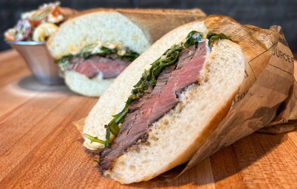 The hanger steak sandwich is a mouthwatering option, featuring tender slices of perfectly cooked steak layered with baby arugula and horseradish, all on a Hoagie roll. It's served alongside a rustic macaroni salad.